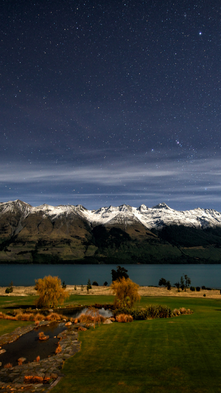Green Grass Field Near Snow Covered Mountain During Night Time. Wallpaper in 750x1334 Resolution