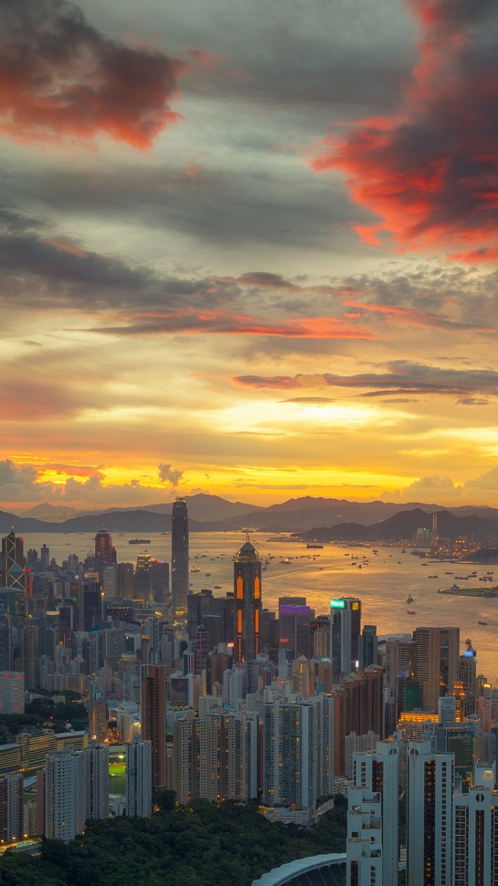 Skyline Der Stadt Unter Orange Und Grau Bewölktem Himmel Bei Sonnenuntergang. Wallpaper in 720x1280 Resolution