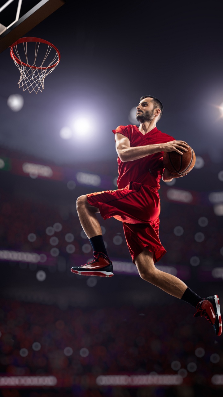 Mann in Rotem Trikot Und Shorts Springt Auf Basketballplatz. Wallpaper in 720x1280 Resolution