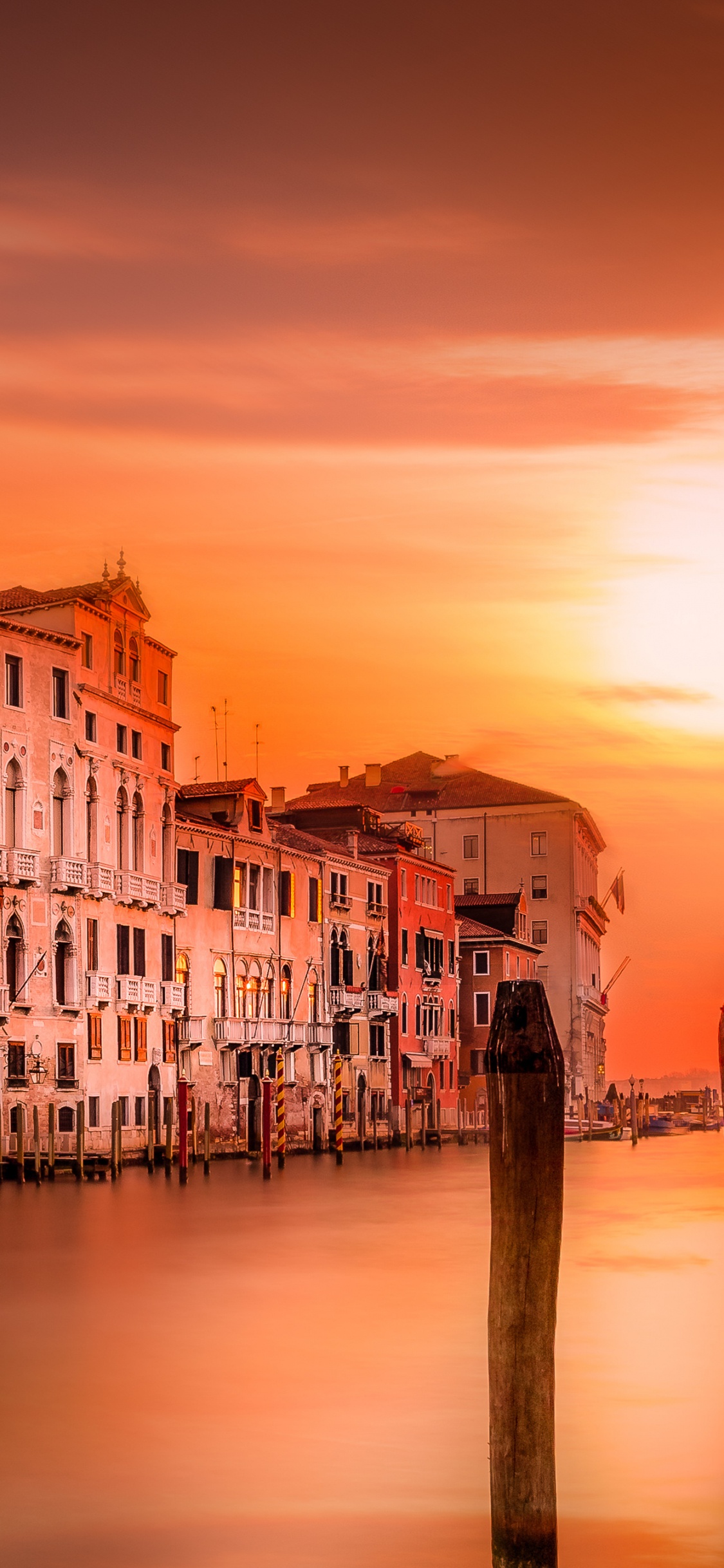 White and Brown Concrete Building Near Body of Water During Sunset. Wallpaper in 1125x2436 Resolution
