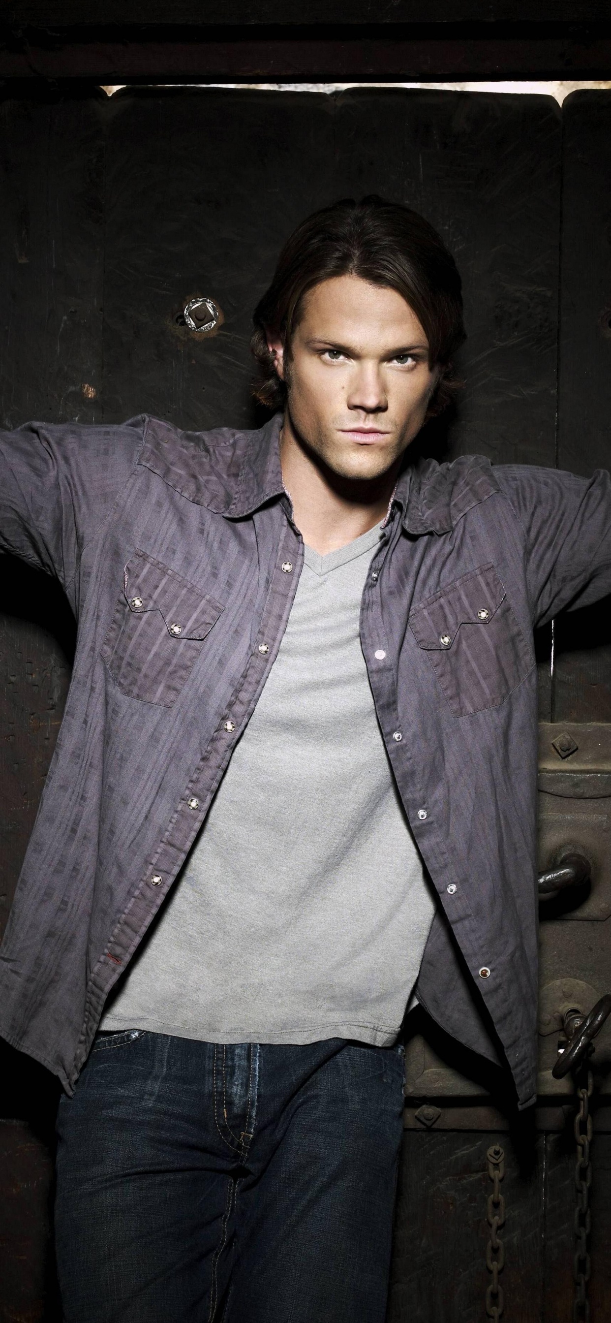 Frau in Blauer Jeansjacke Neben Brauner Holztür. Wallpaper in 1242x2688 Resolution