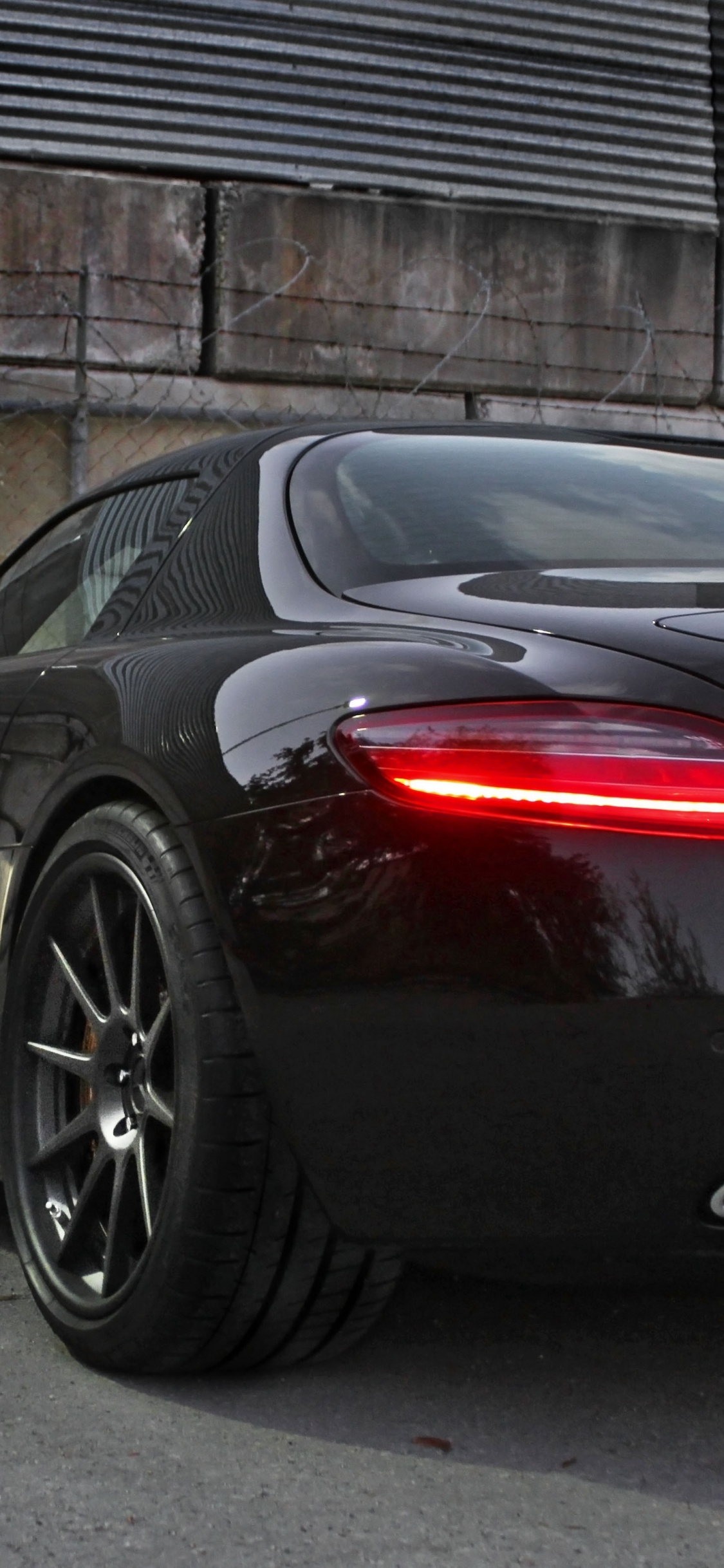 Ferrari 458 Italia Negro y Rojo Estacionado Junto a la Valla de Metal Gris. Wallpaper in 1125x2436 Resolution