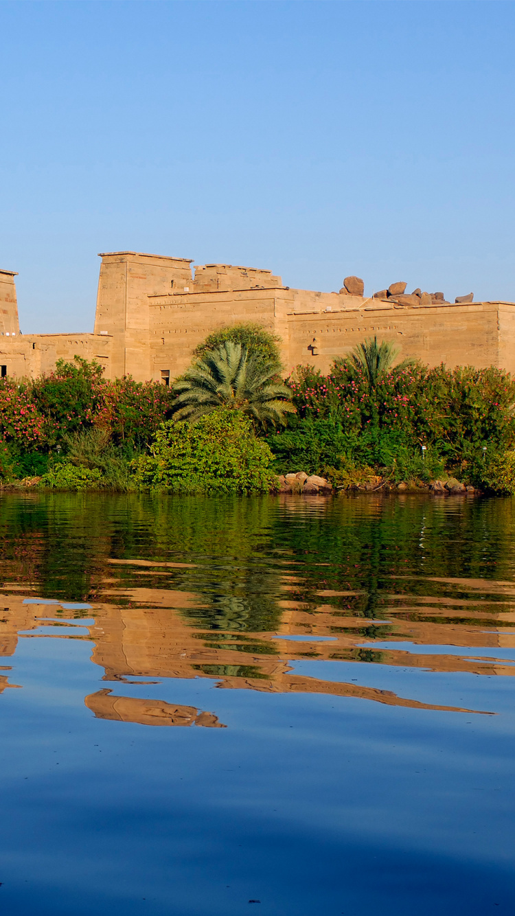 Brown Concrete Building Near Body of Water During Daytime. Wallpaper in 750x1334 Resolution