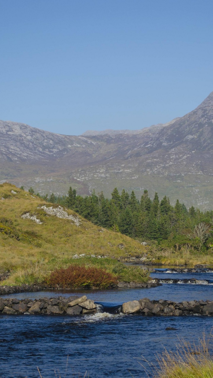 Green Grass Field Near Body of Water and Mountain Under Blue Sky During Daytime. Wallpaper in 720x1280 Resolution