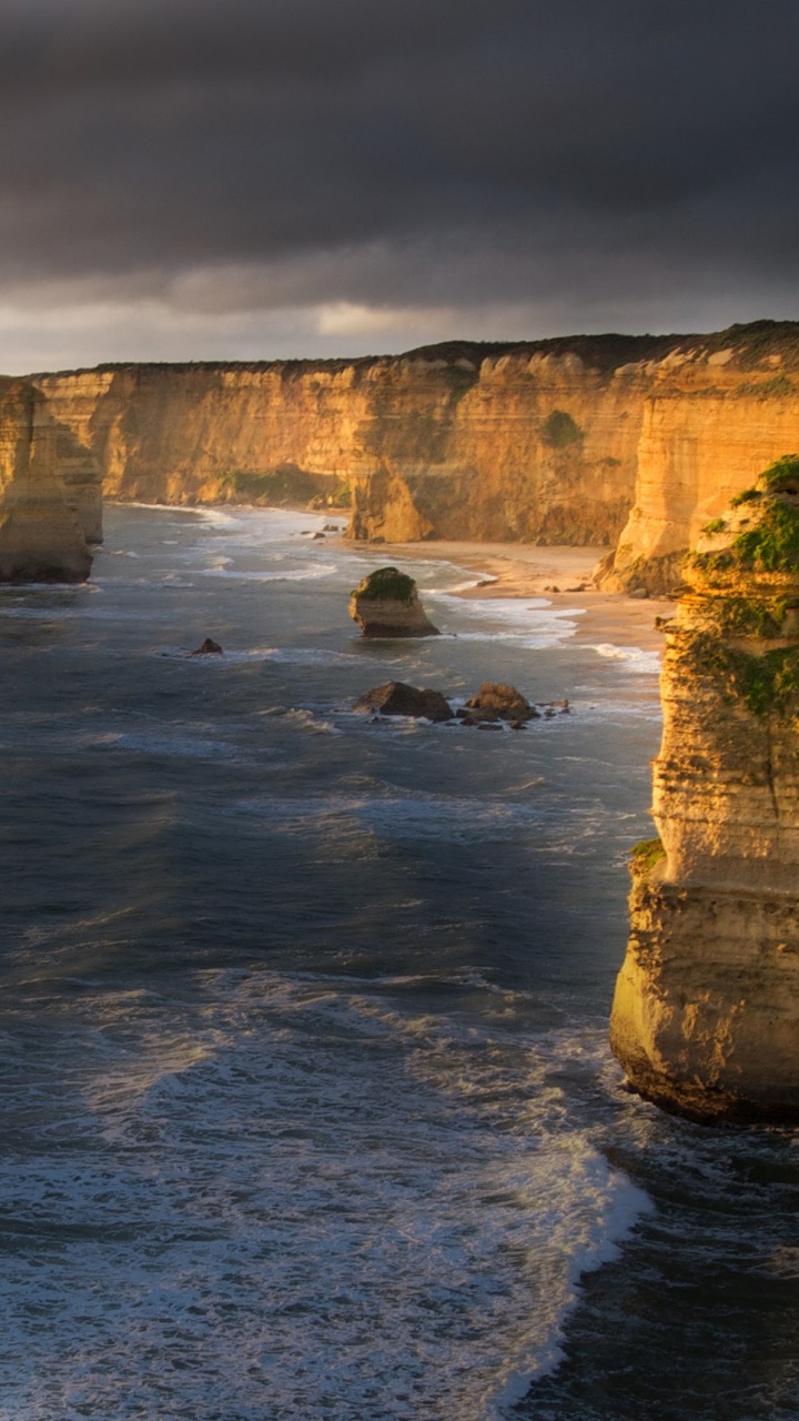 Grauer Felsiger Berg Neben Gewässer Tagsüber. Wallpaper in 720x1280 Resolution