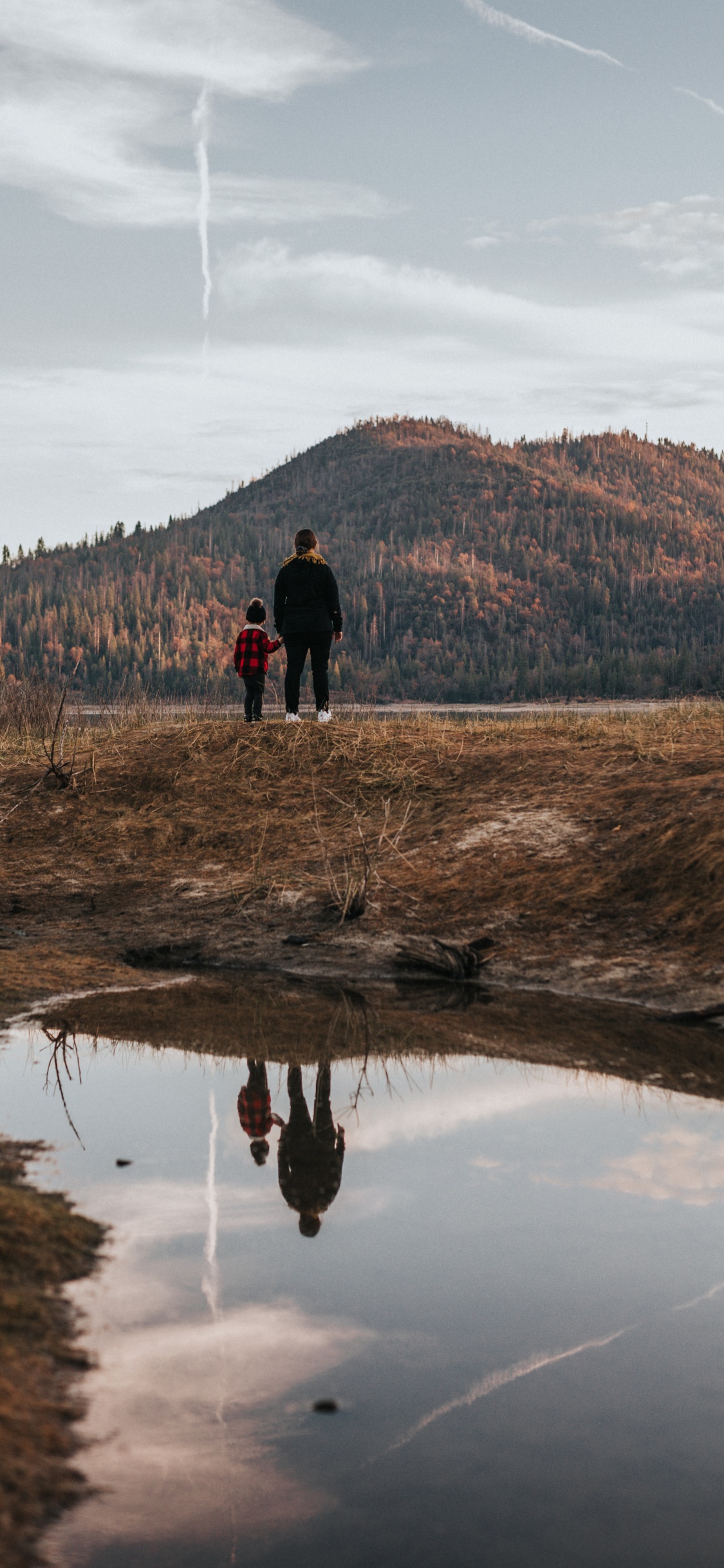 2 Person Standing on Brown Grass Field Near Lake During Daytime. Wallpaper in 1125x2436 Resolution