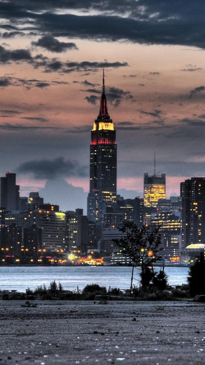 Skyline Der Stadt Über Gewässer Während Der Nacht. Wallpaper in 720x1280 Resolution