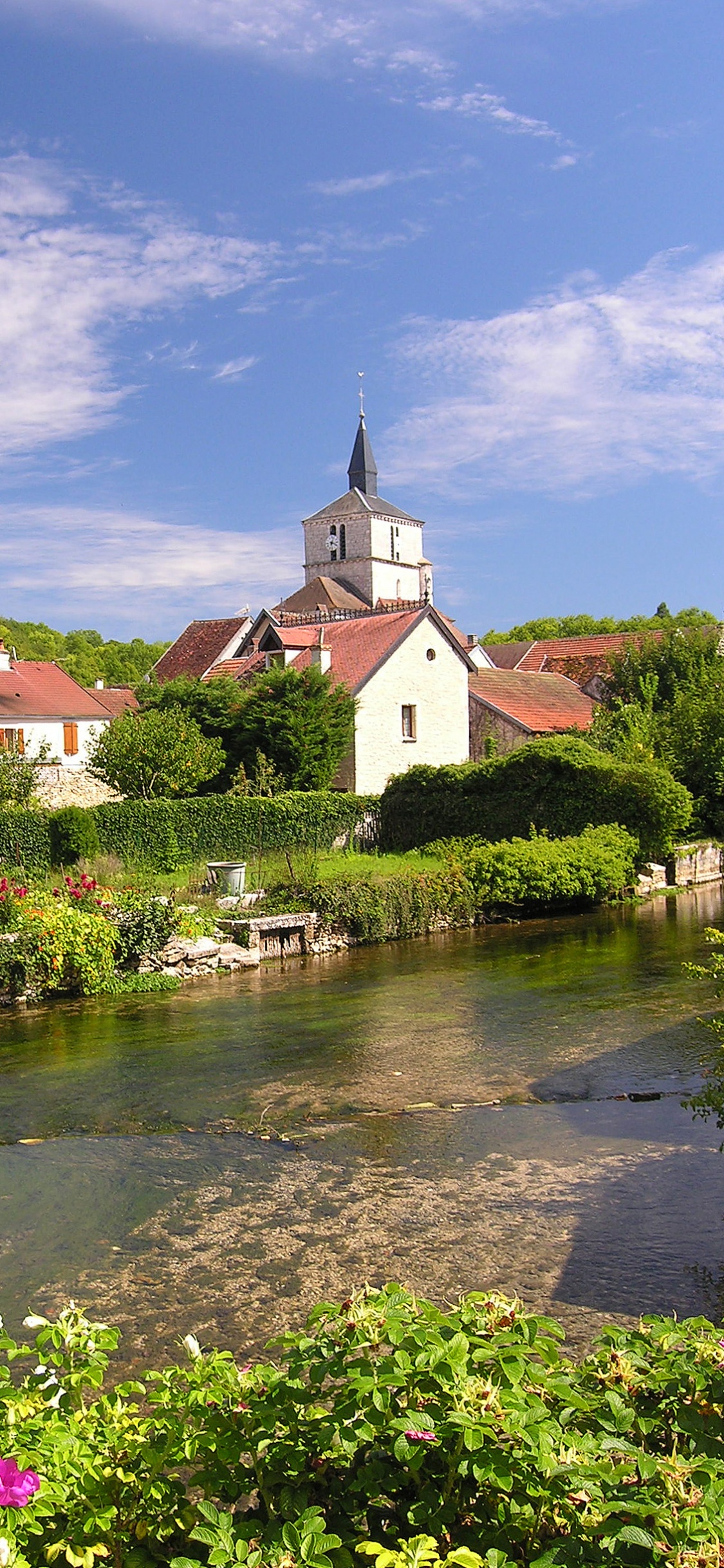 Weißes Und Braunes Betongebäude in Der Nähe Des Flusses Unter Blauem Himmel Tagsüber. Wallpaper in 1125x2436 Resolution