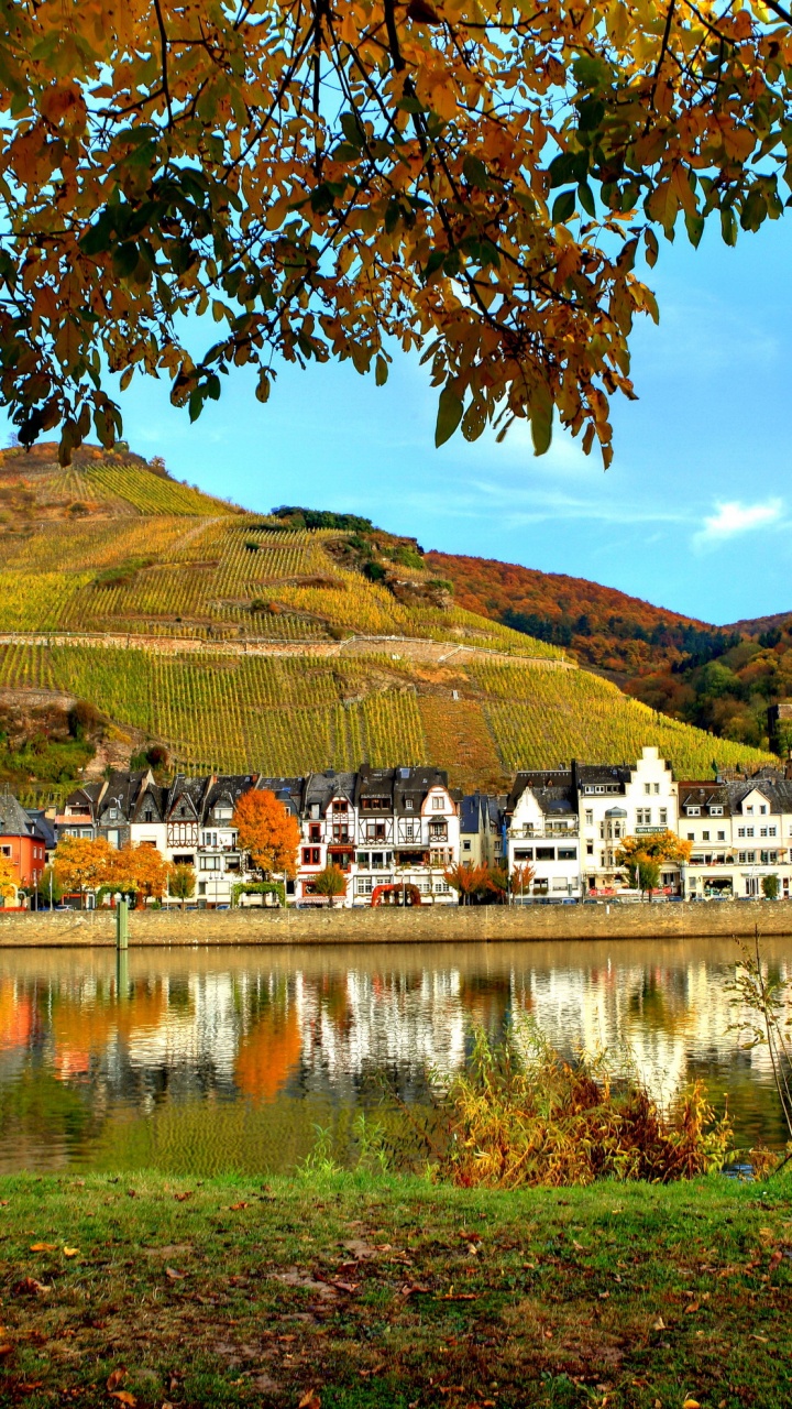 Weißes Betongebäude in Der Nähe Von See Und Grünem Grasfeld Tagsüber. Wallpaper in 720x1280 Resolution