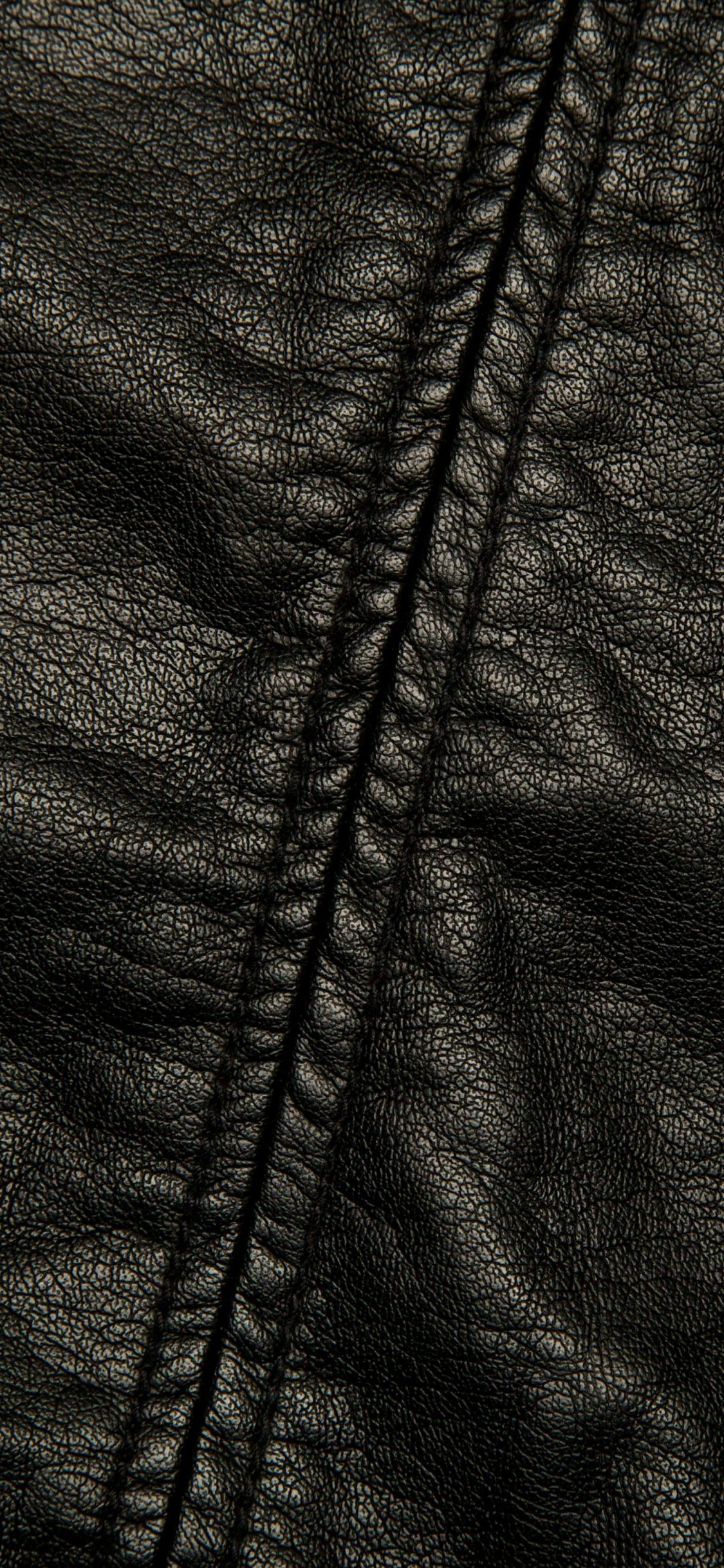 Chaqueta Negra Con Cremallera Sobre Textil Blanco. Wallpaper in 1125x2436 Resolution