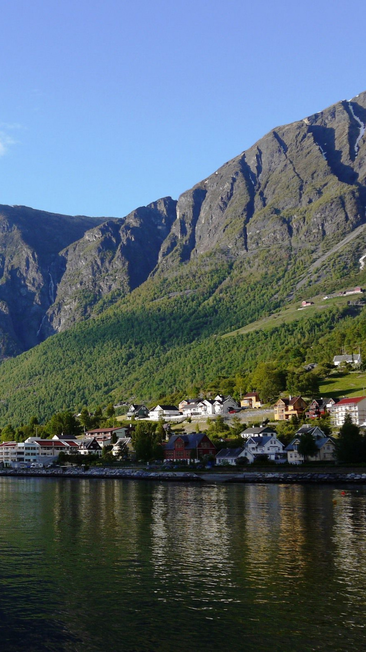 Montañas Verdes Junto al Cuerpo de Agua Bajo un Cielo Azul Durante el Día. Wallpaper in 750x1334 Resolution