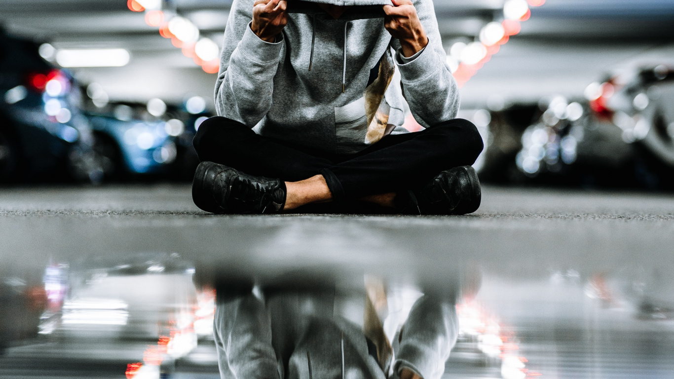 Person in Black Jacket and Pants Sitting on Road During Night Time. Wallpaper in 1366x768 Resolution