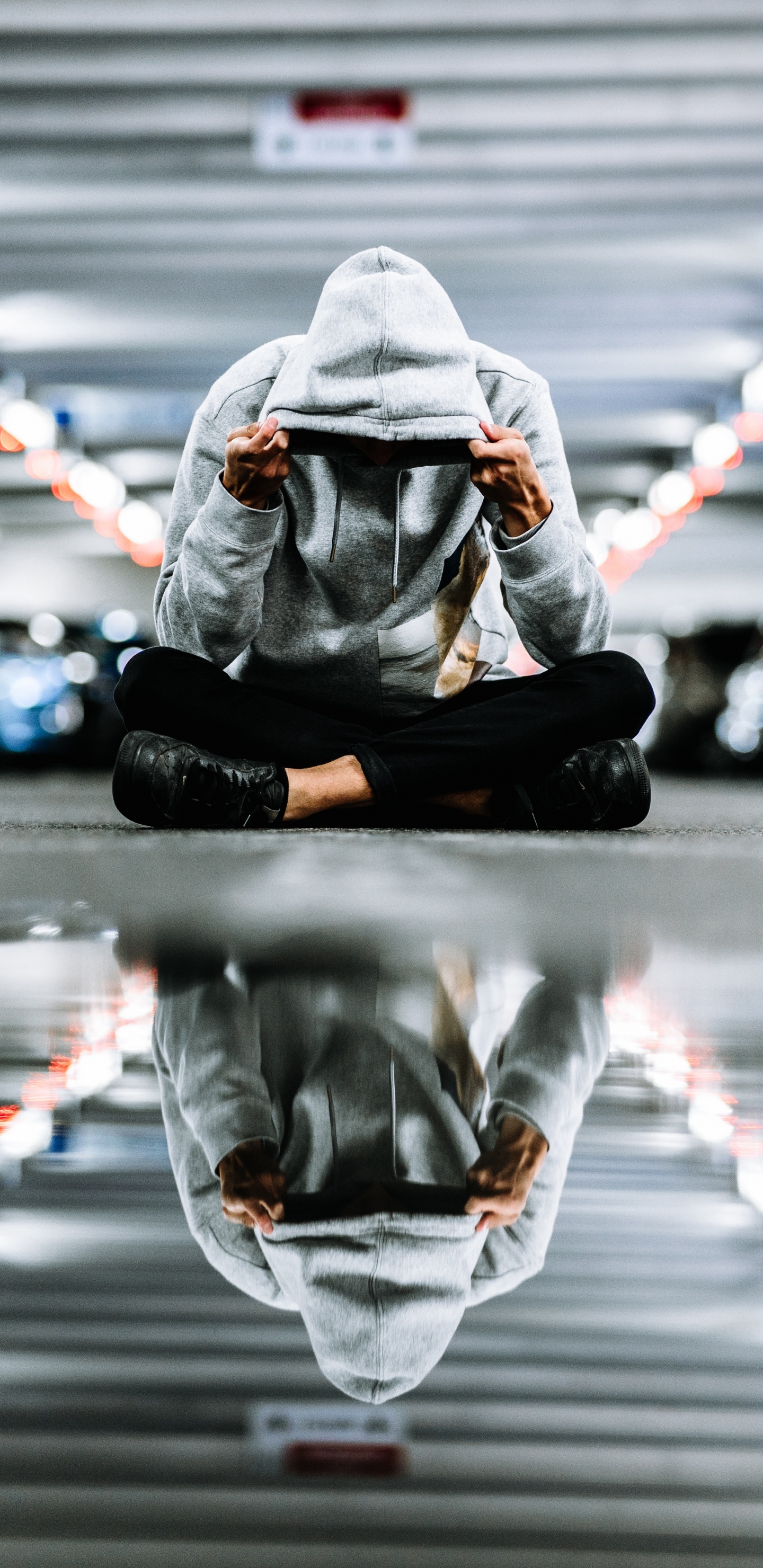 Person in Black Jacket and Pants Sitting on Road During Night Time. Wallpaper in 1440x2960 Resolution
