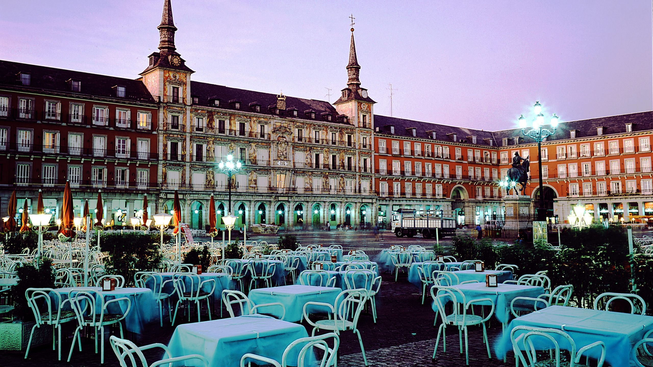 White and Blue Chairs and Tables Near Brown Concrete Building During Night Time. Wallpaper in 2560x1440 Resolution