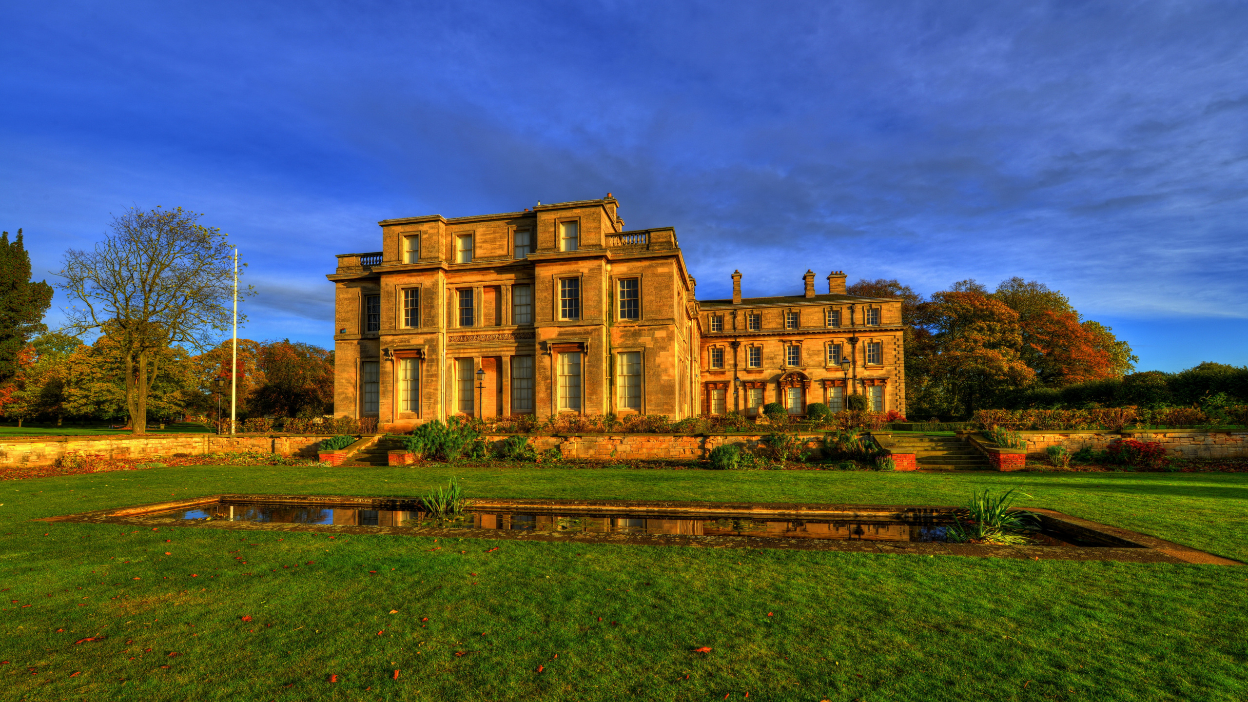 Brown Concrete Building Near Green Grass Field Under Blue Sky During Daytime. Wallpaper in 2560x1440 Resolution