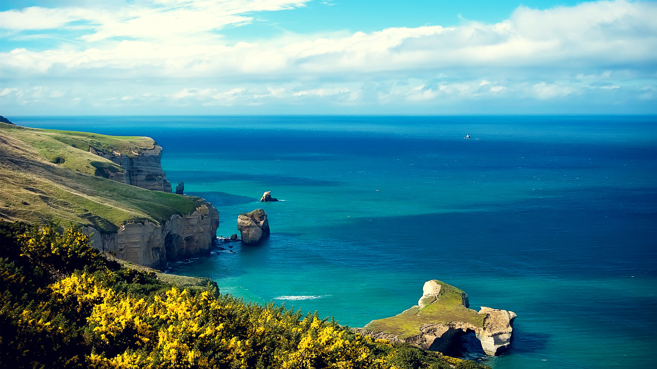 Green and Brown Rock Formation Beside Blue Sea Under Blue and White Cloudy Sky During Daytime. Wallpaper in 1280x720 Resolution