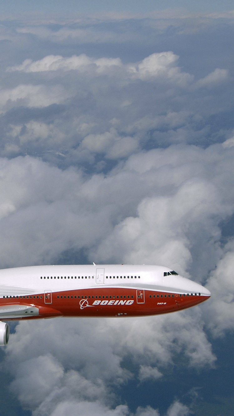 Weißes Und Rotes Flugzeug, Das Tagsüber Unter Bewölktem Himmel Fliegt. Wallpaper in 750x1334 Resolution