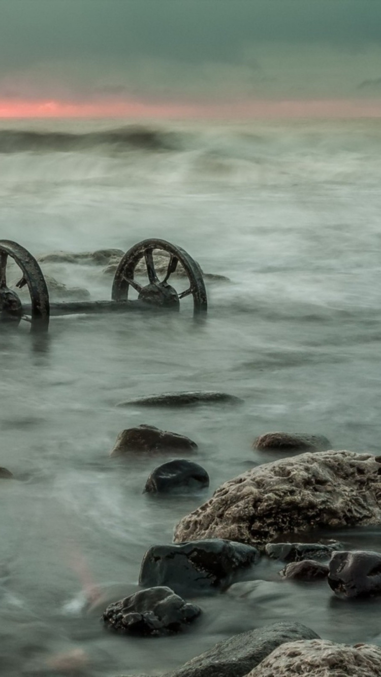 Black and Gray Rocks on Body of Water. Wallpaper in 750x1334 Resolution