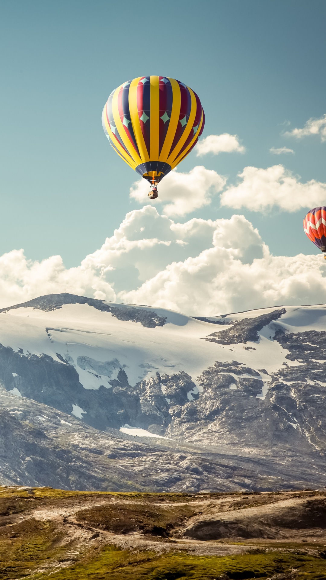 Gelber Und Grüner Heißluftballon, Der Tagsüber Über Schneebedeckte Berge Fliegt. Wallpaper in 1080x1920 Resolution