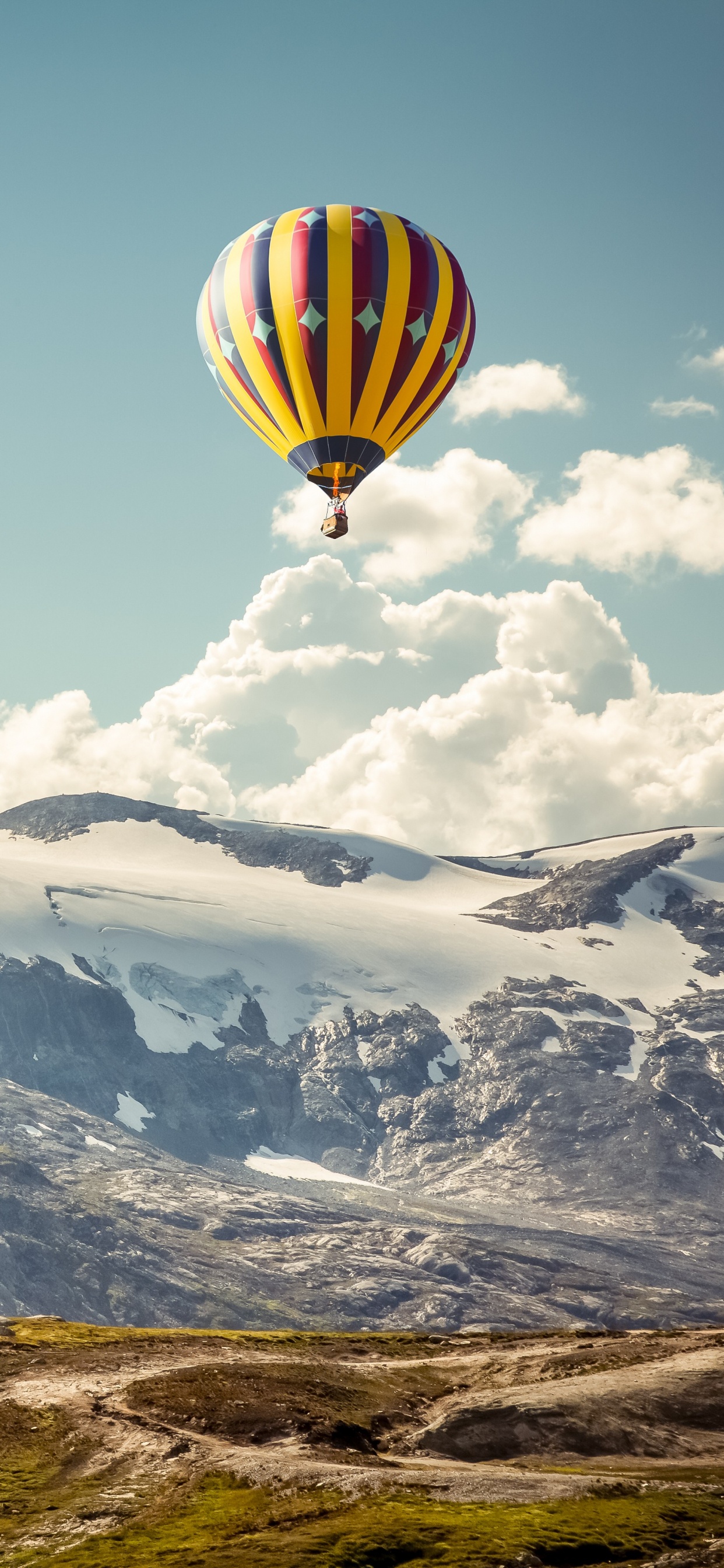 Gelber Und Grüner Heißluftballon, Der Tagsüber Über Schneebedeckte Berge Fliegt. Wallpaper in 1242x2688 Resolution