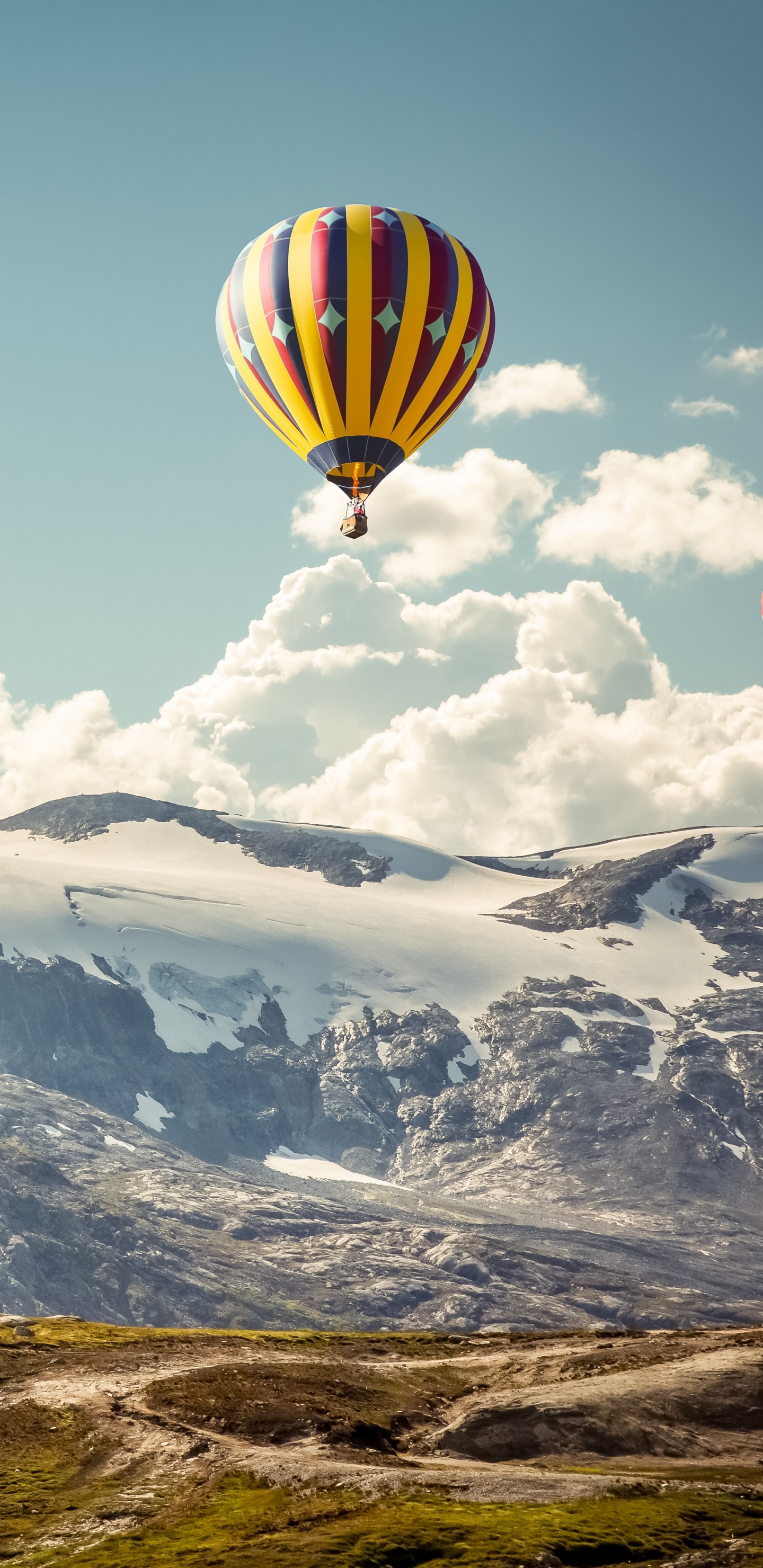 Gelber Und Grüner Heißluftballon, Der Tagsüber Über Schneebedeckte Berge Fliegt. Wallpaper in 1440x2960 Resolution