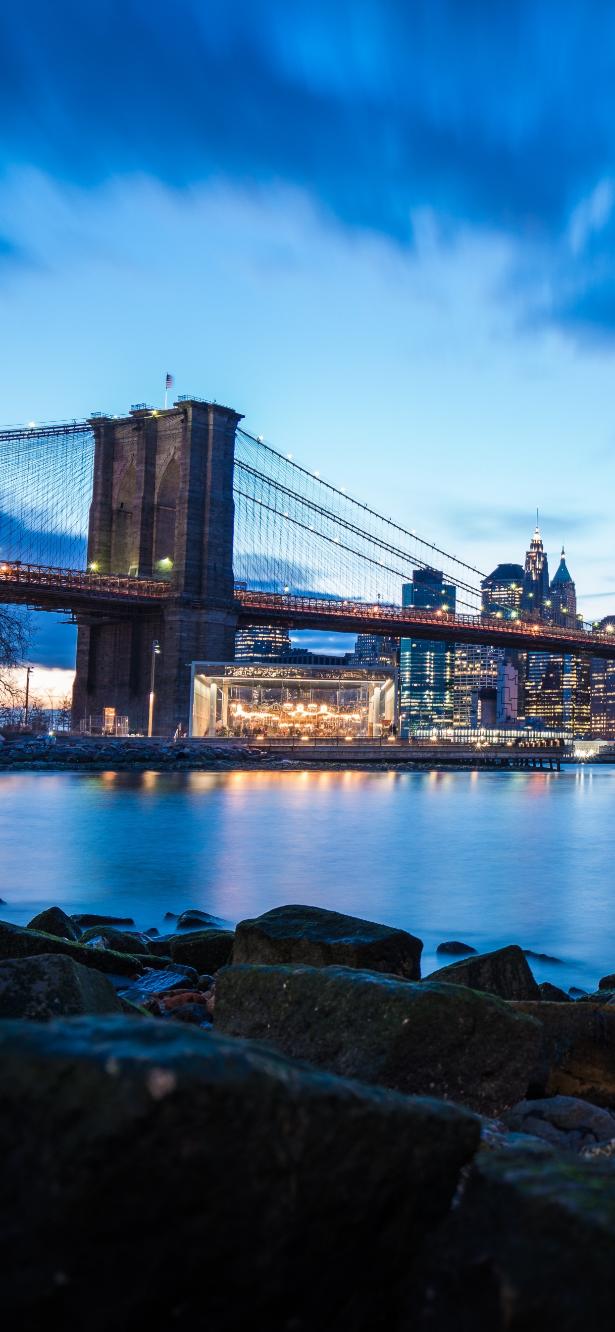 Puente Sobre el Agua Cerca de Los Edificios de la Ciudad Durante la Noche. Wallpaper in 1242x2688 Resolution