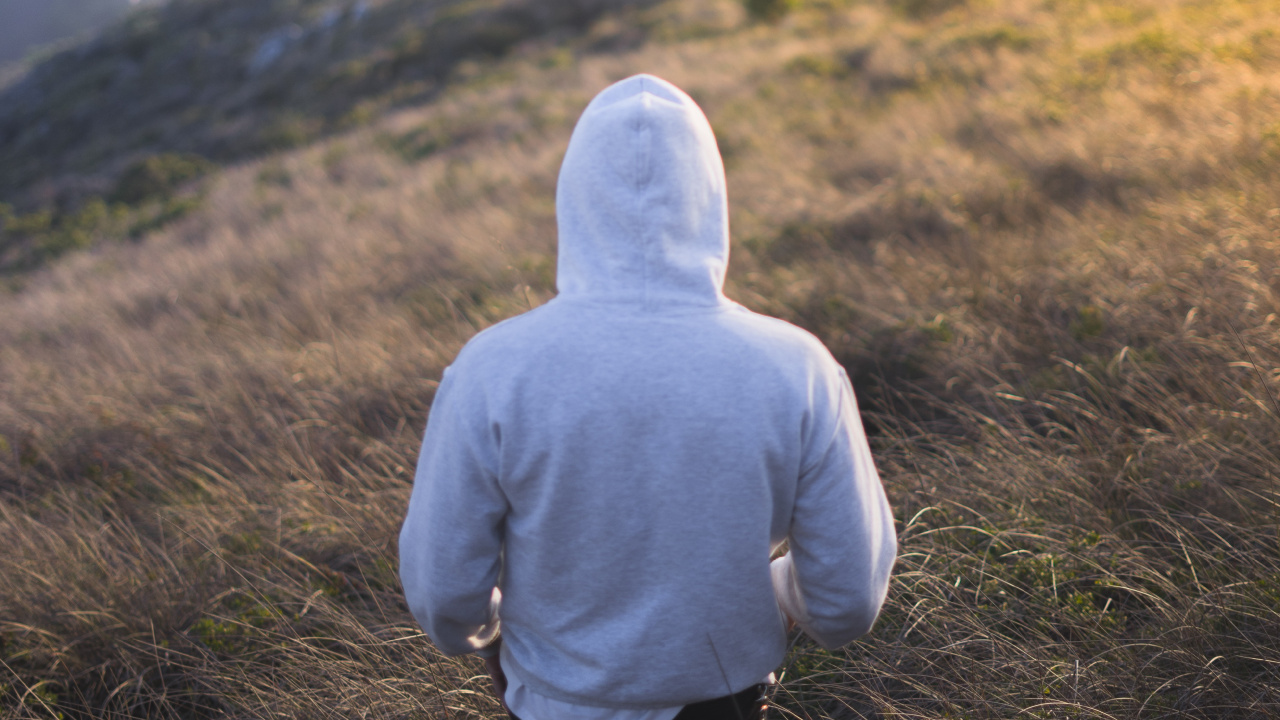 Person in Gray Hoodie Standing on Green Grass Field During Daytime. Wallpaper in 1280x720 Resolution