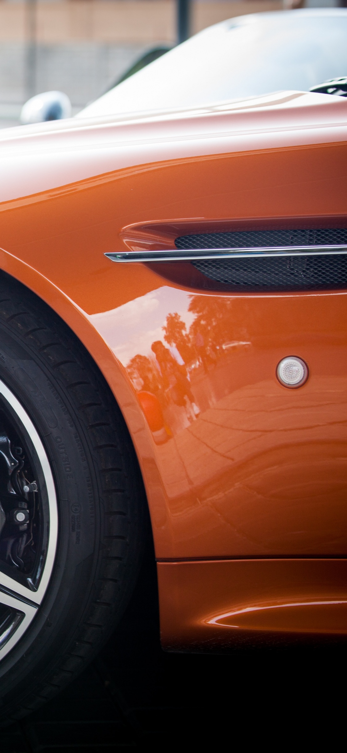 Coche Naranja y Negro Sobre Pavimento Gris. Wallpaper in 1125x2436 Resolution