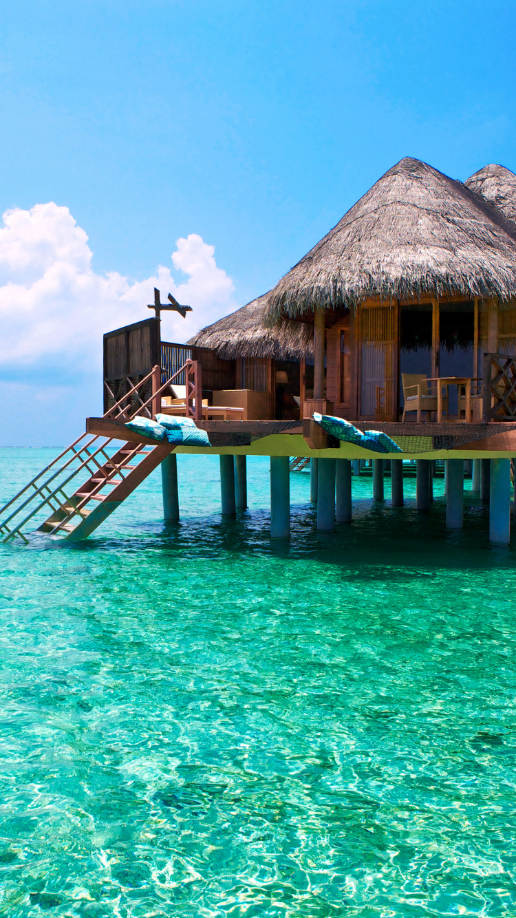 Brown Wooden Beach House on Blue Sea Under Blue Sky During Daytime. Wallpaper in 750x1334 Resolution