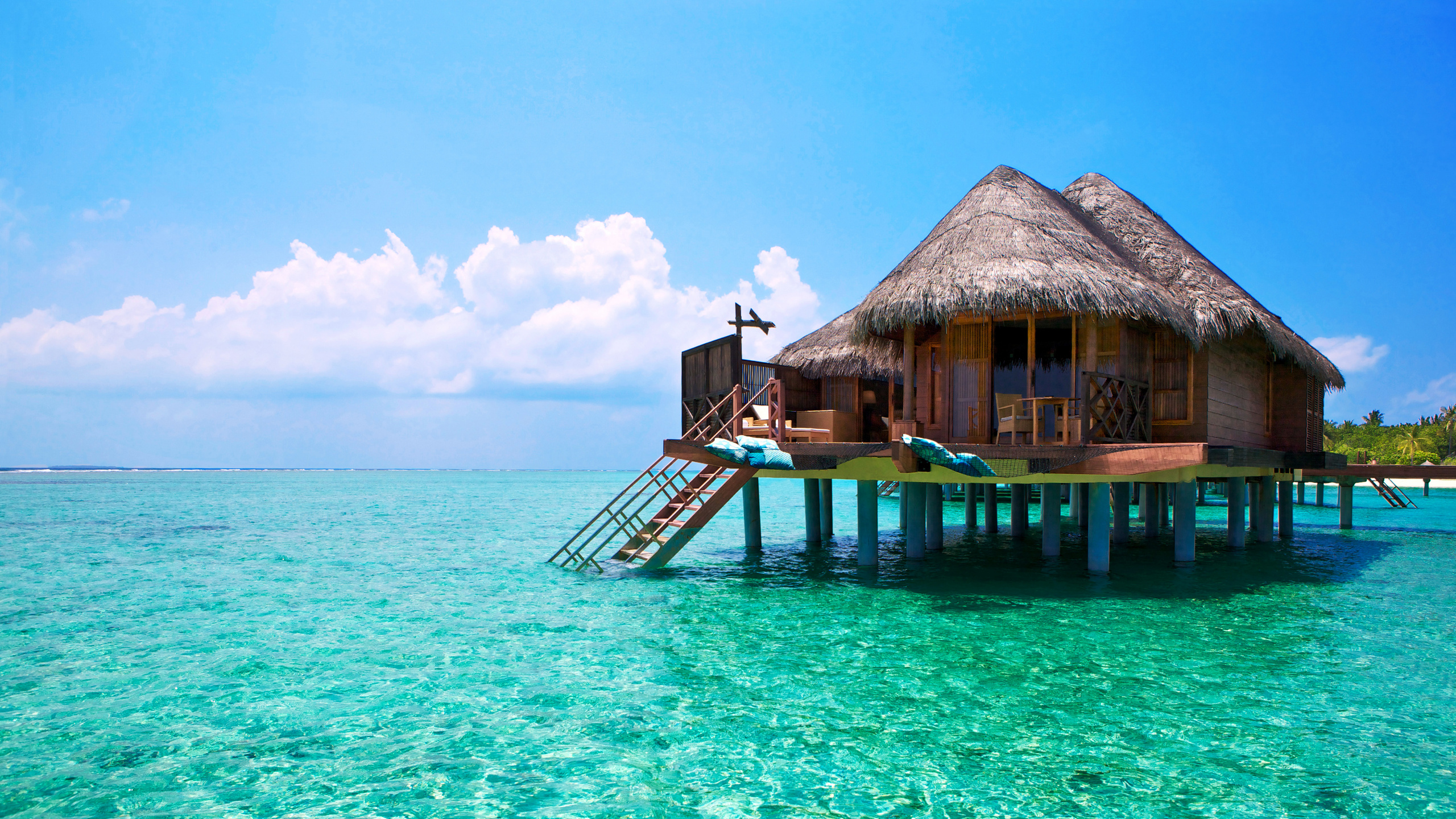Maison de Plage en Bois Marron Sur Mer Bleue Sous Ciel Bleu Pendant la Journée. Wallpaper in 2560x1440 Resolution