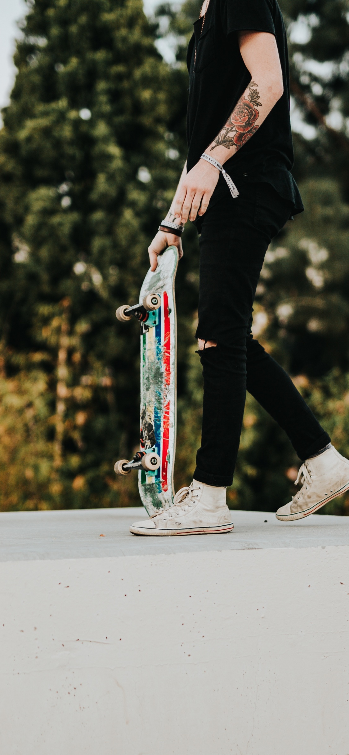 Mann in Schwarzer Hose Und Schwarzer Jacke, Der Skateboard Fährt. Wallpaper in 1125x2436 Resolution