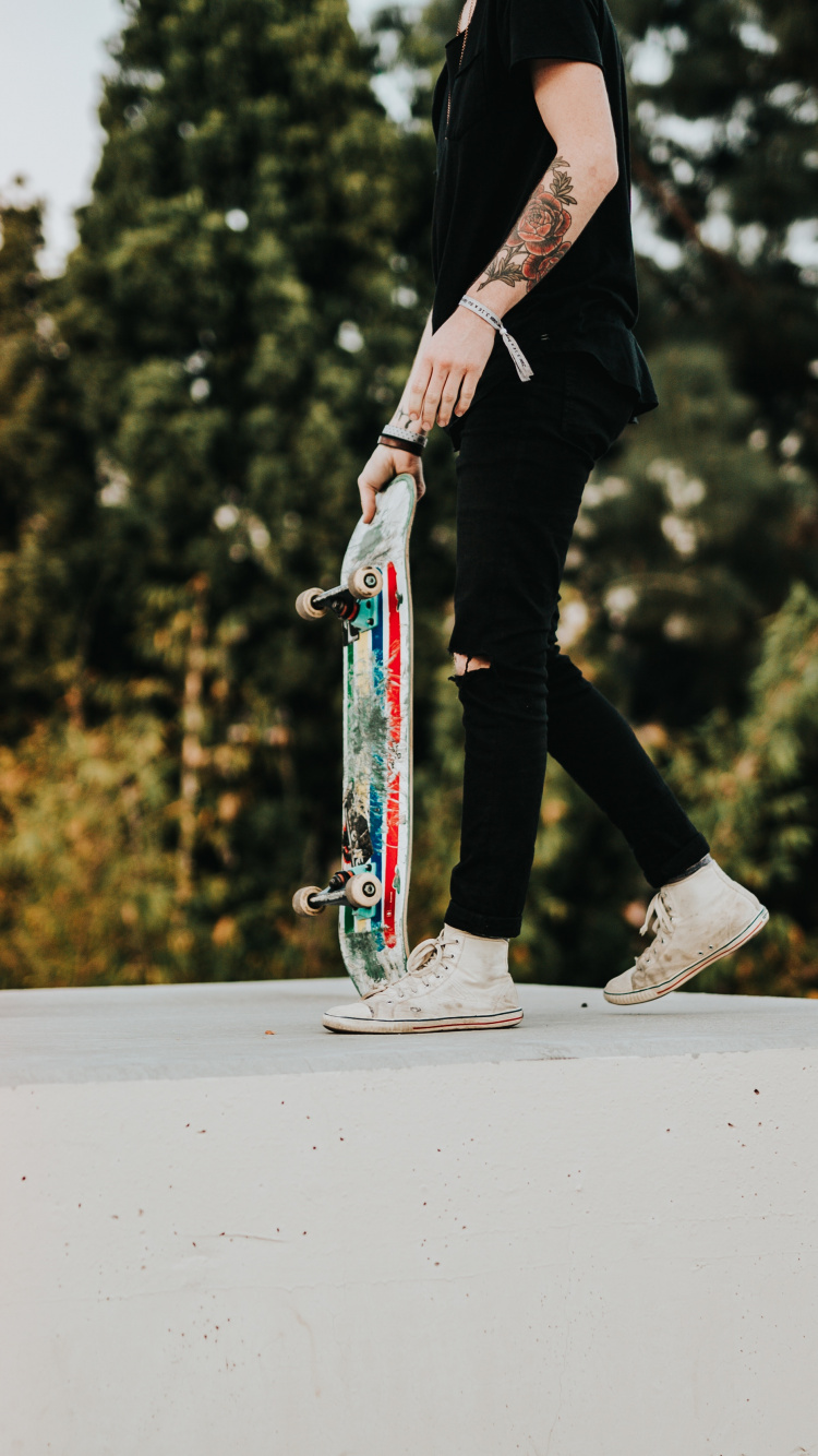 Mann in Schwarzer Hose Und Schwarzer Jacke, Der Skateboard Fährt. Wallpaper in 750x1334 Resolution