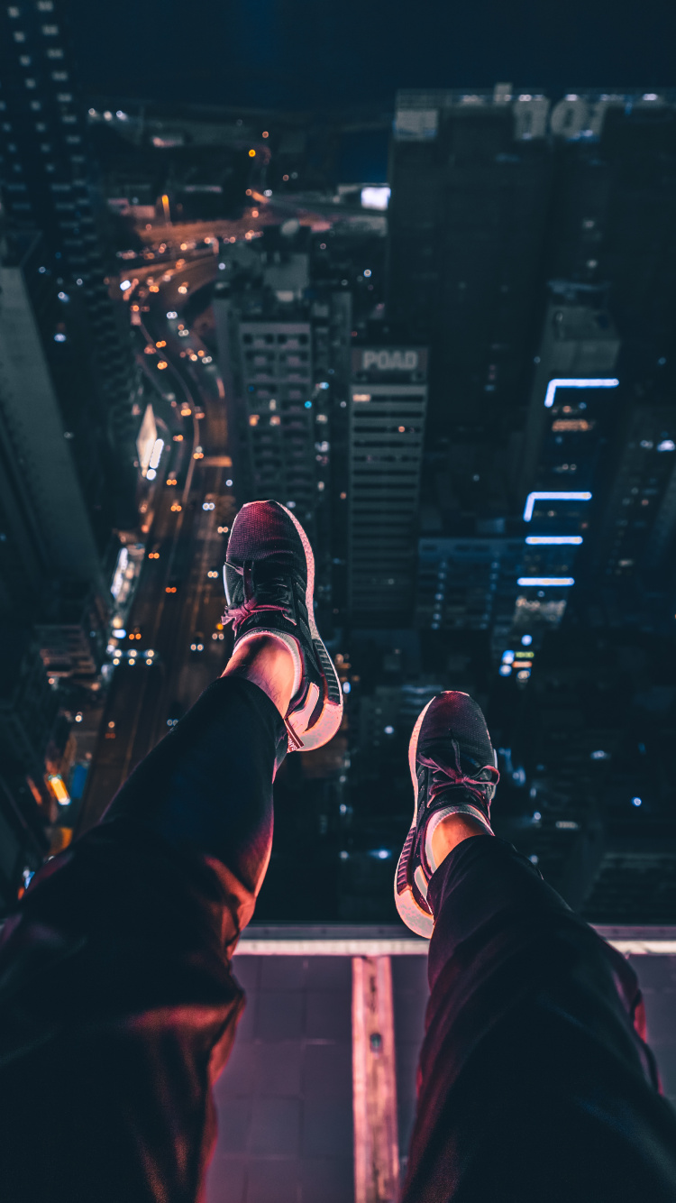 Personne en Pantalon Noir et Baskets Noires et Blanches Assises Sur le Bâtiment Pendant la Nuit. Wallpaper in 750x1334 Resolution