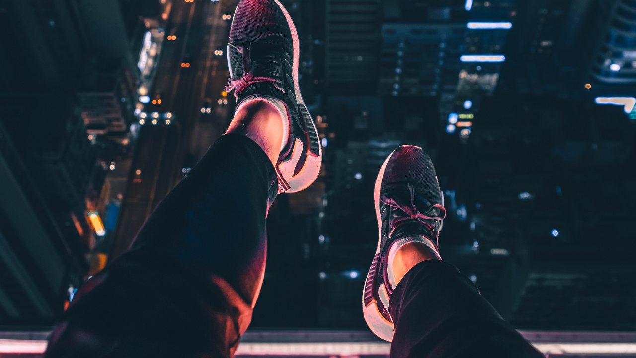 Person in Black Pants and Black and White Sneakers Sitting on Building During Night Time. Wallpaper in 1280x720 Resolution