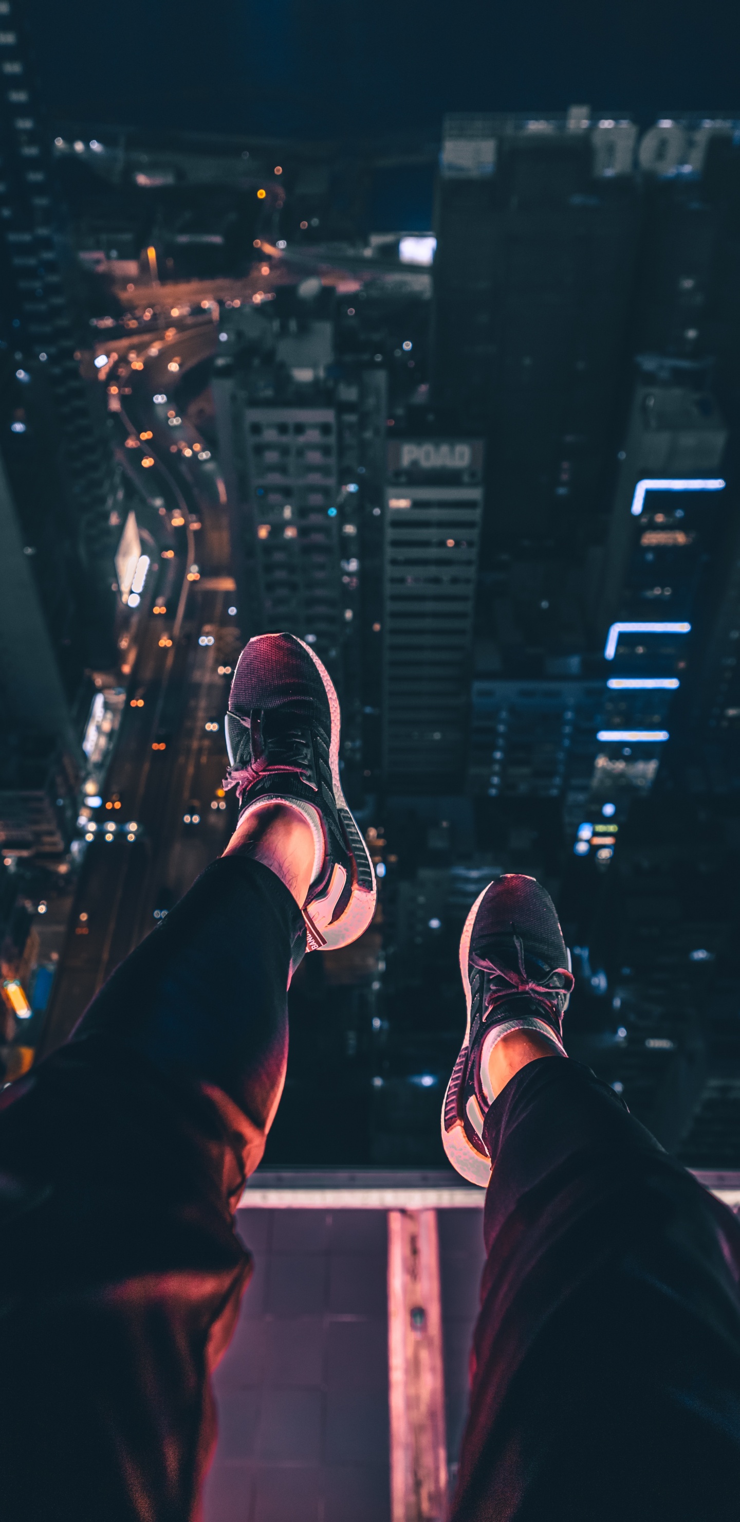 Person in Schwarzen Hosen Und Schwarz-weißen Turnschuhen, Die Nachts Auf Dem Gebäude Sitzt. Wallpaper in 1440x2960 Resolution