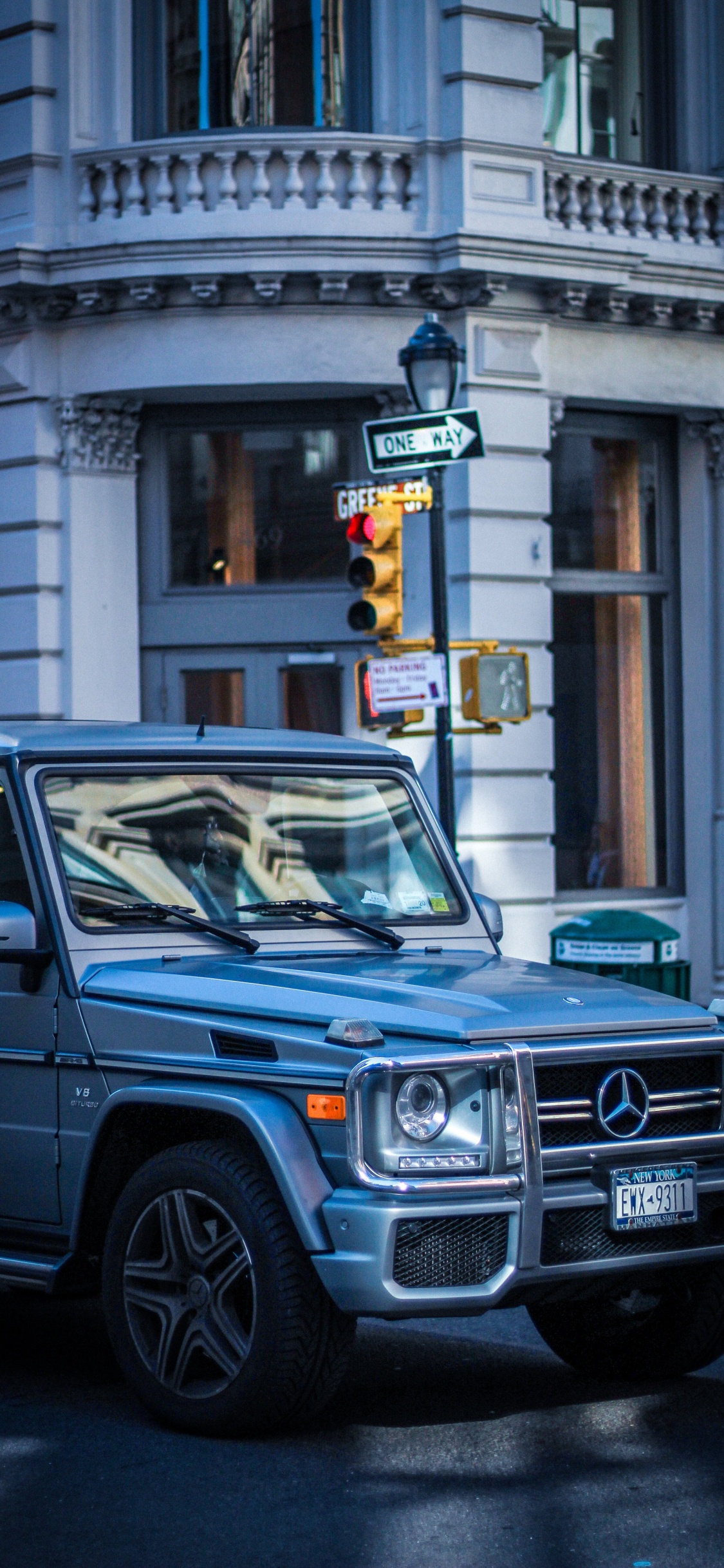 Blauer Mercedes-Benz G-Klasse-Geländewagen, Der Tagsüber Neben Einem Weißen Betongebäude Geparkt Ist?. Wallpaper in 1125x2436 Resolution