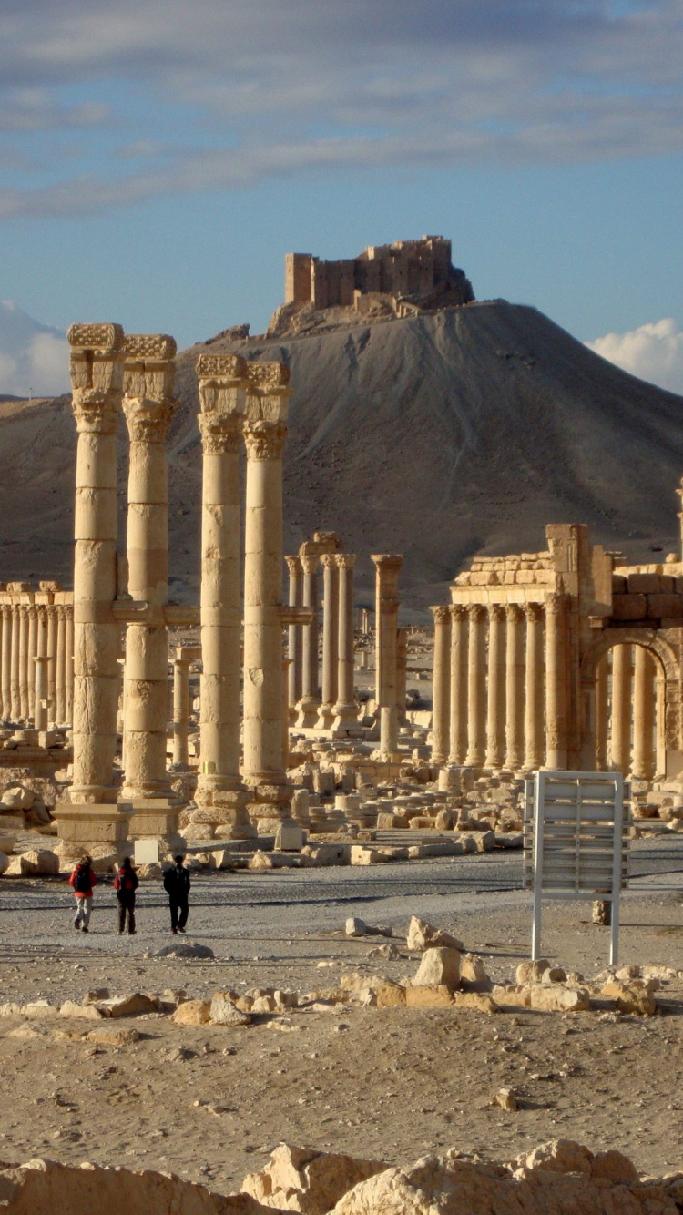 Personnes Marchant Sur du Sable Brun Près D'un Bâtiment en Béton Brun Pendant la Journée. Wallpaper in 750x1334 Resolution