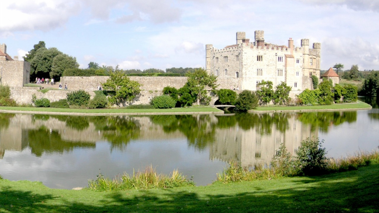 Gray Concrete Building Near Green Grass Field and Lake Under White Clouds and Blue Sky During. Wallpaper in 1280x720 Resolution