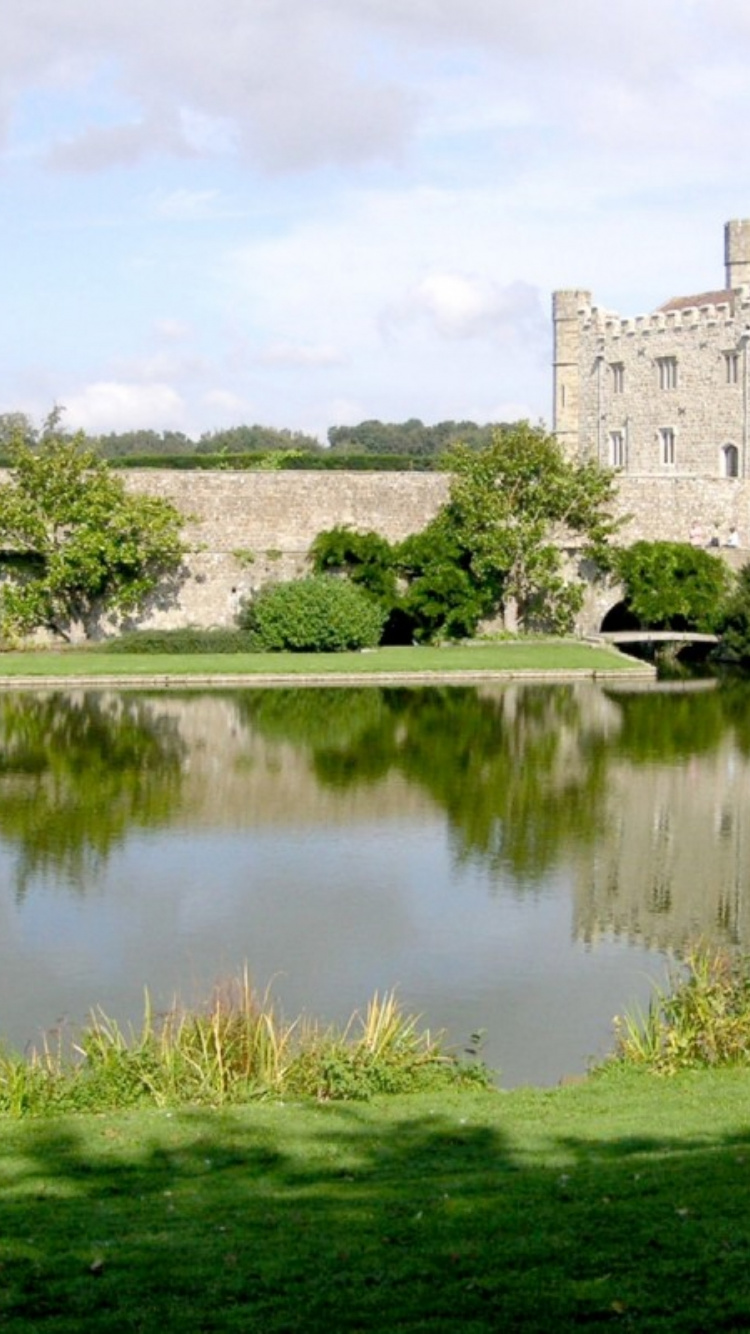 Gray Concrete Building Near Green Grass Field and Lake Under White Clouds and Blue Sky During. Wallpaper in 750x1334 Resolution