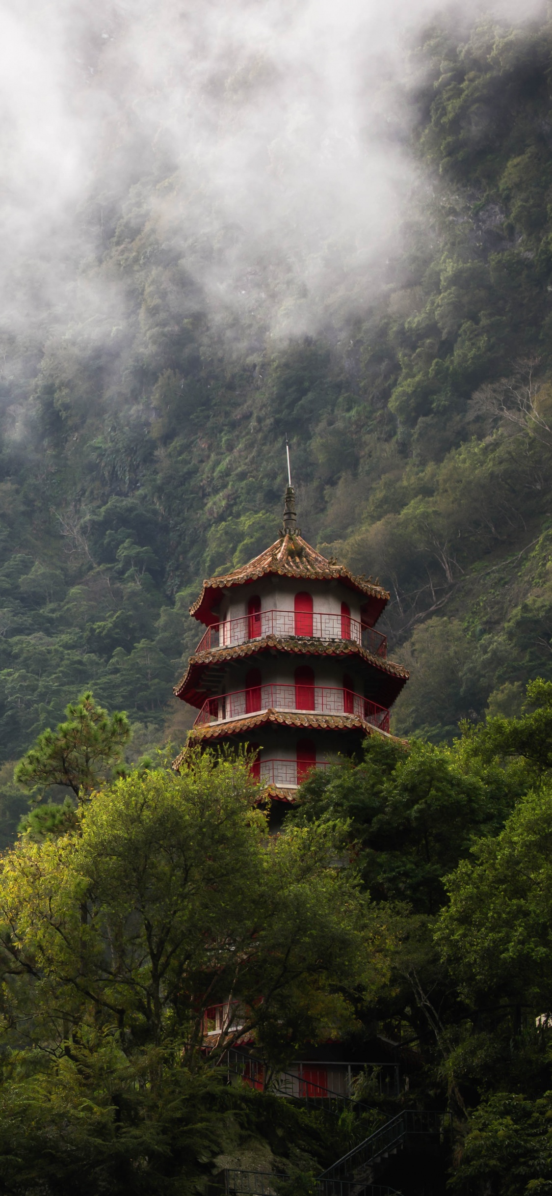 Torre Marrón y Negra en la Cima de la Montaña Verde. Wallpaper in 1125x2436 Resolution