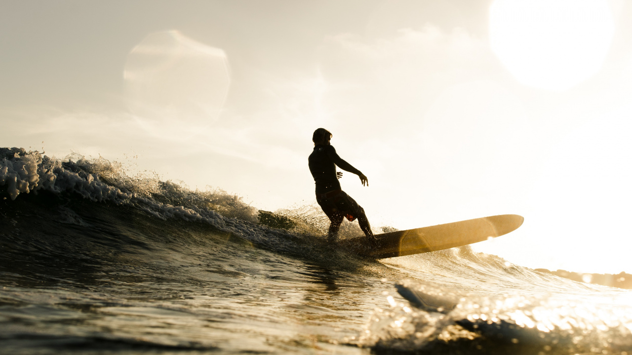 Silhouette Eines Mannes, Der Tagsüber Ein Surfbrett Auf Dem Wasser Hält. Wallpaper in 1280x720 Resolution