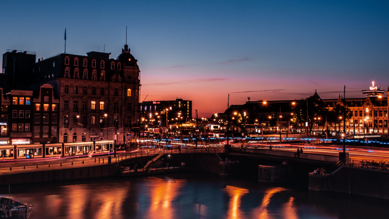 Braunes Betongebäude in Der Nähe Des Flusses Während Der Nachtzeit. Wallpaper in 1280x720 Resolution