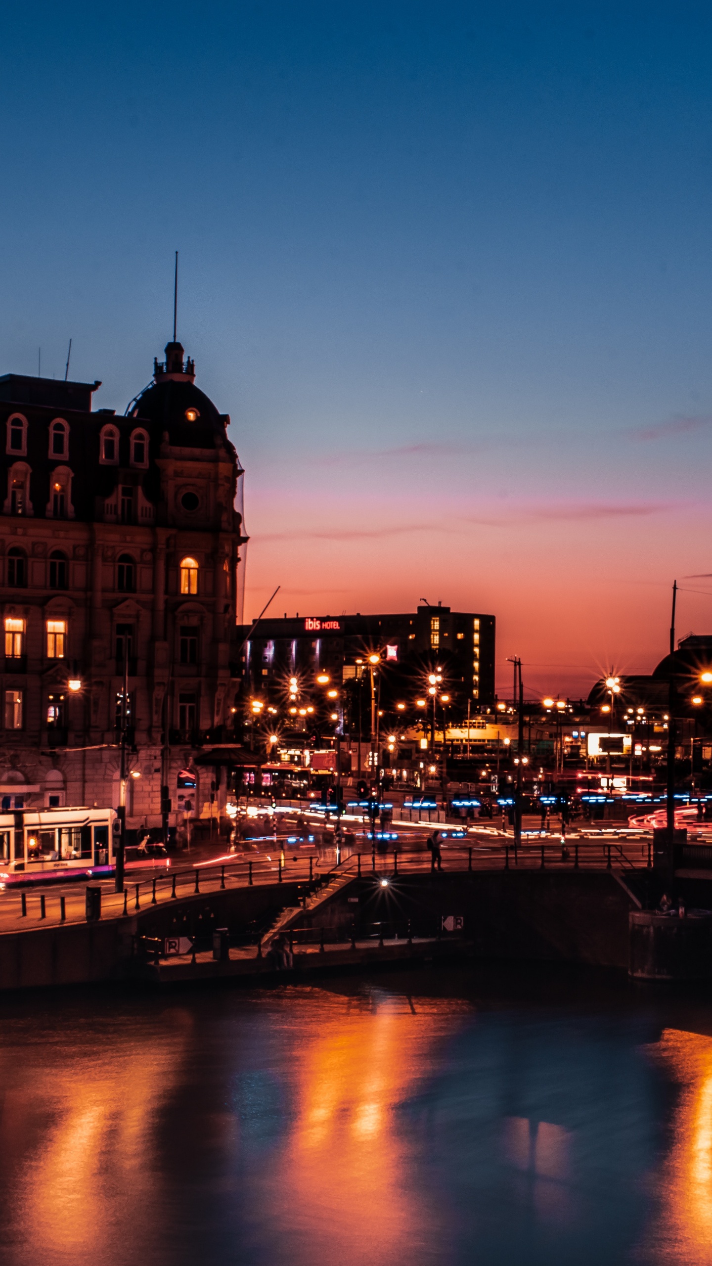 Braunes Betongebäude in Der Nähe Des Flusses Während Der Nachtzeit. Wallpaper in 1440x2560 Resolution