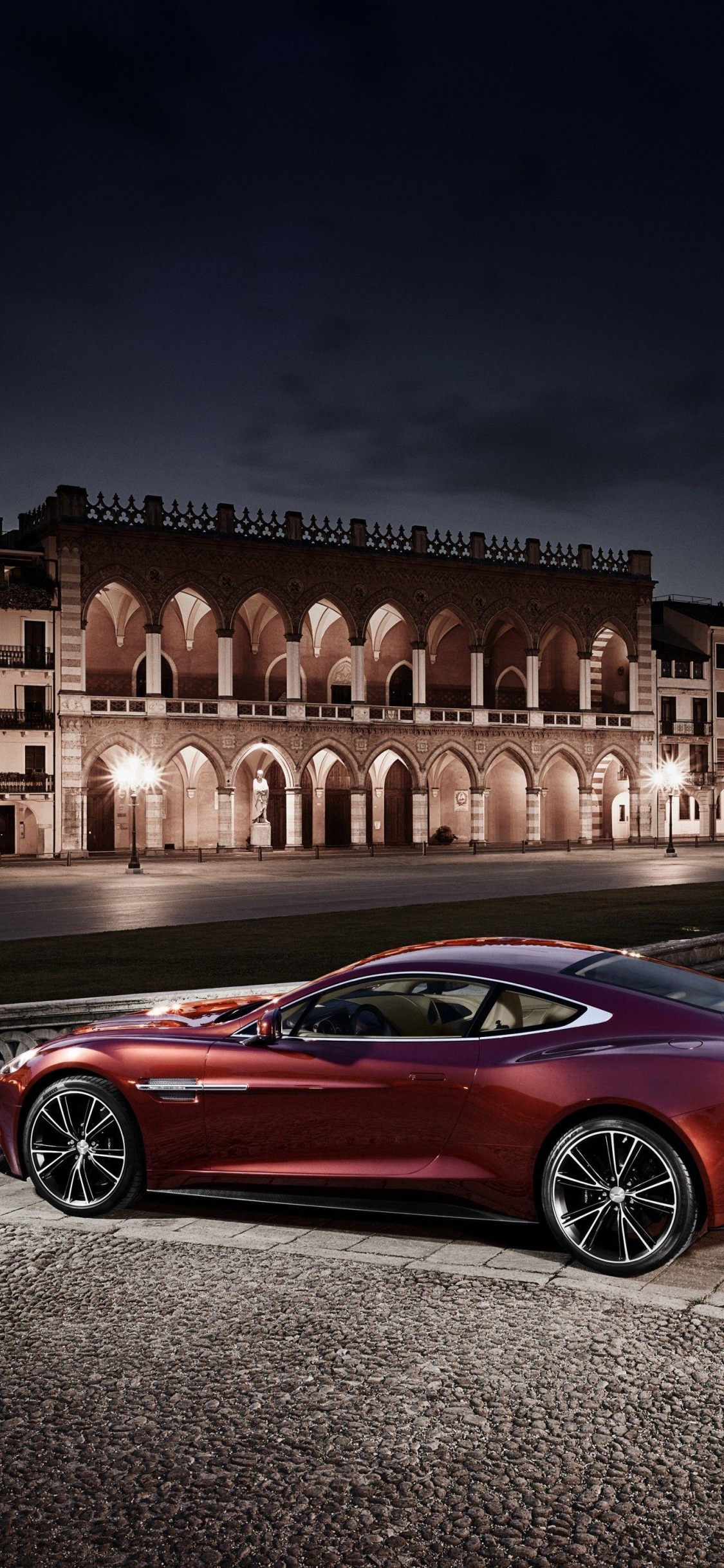 Coupe Rojo Estacionado en la Acera Durante la Noche. Wallpaper in 1125x2436 Resolution