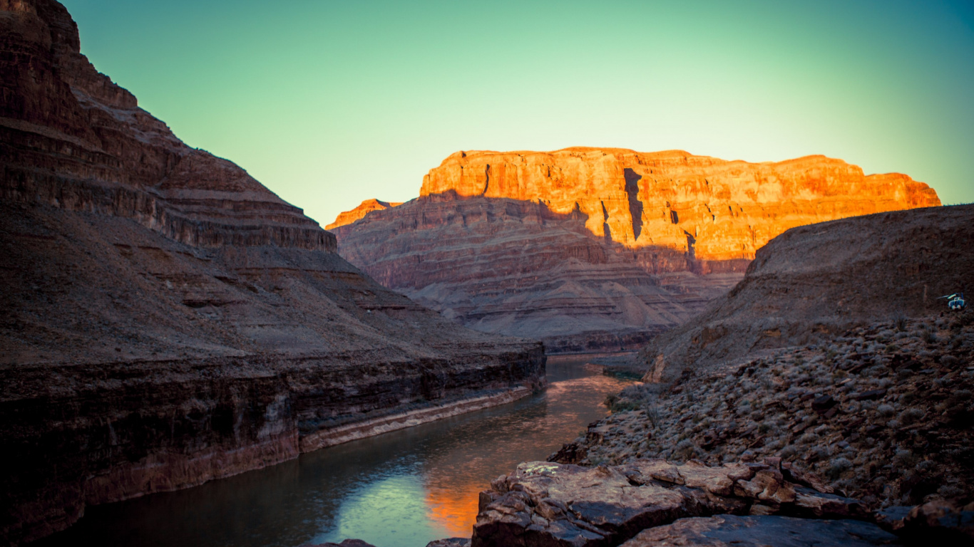 Brown Rocky Mountain Beside Body of Water During Daytime. Wallpaper in 1366x768 Resolution