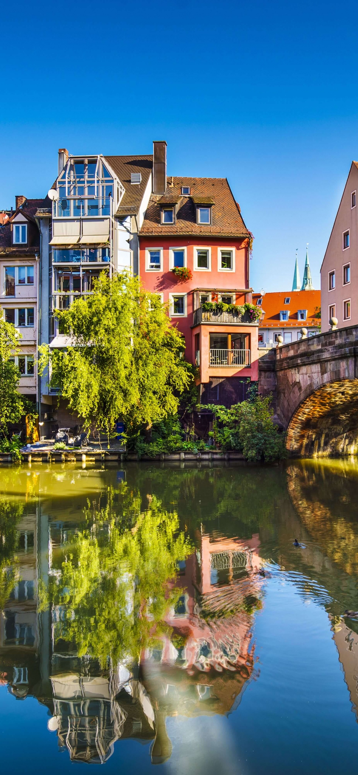 Brown Concrete Building Near River During Daytime. Wallpaper in 1242x2688 Resolution