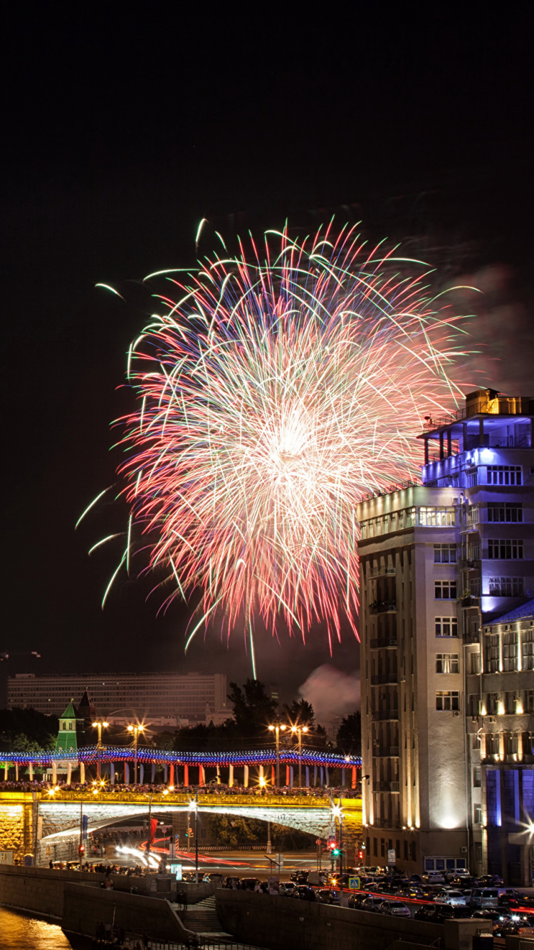 Feuerwerk Über Stadtgebäuden Während Der Nacht. Wallpaper in 750x1334 Resolution