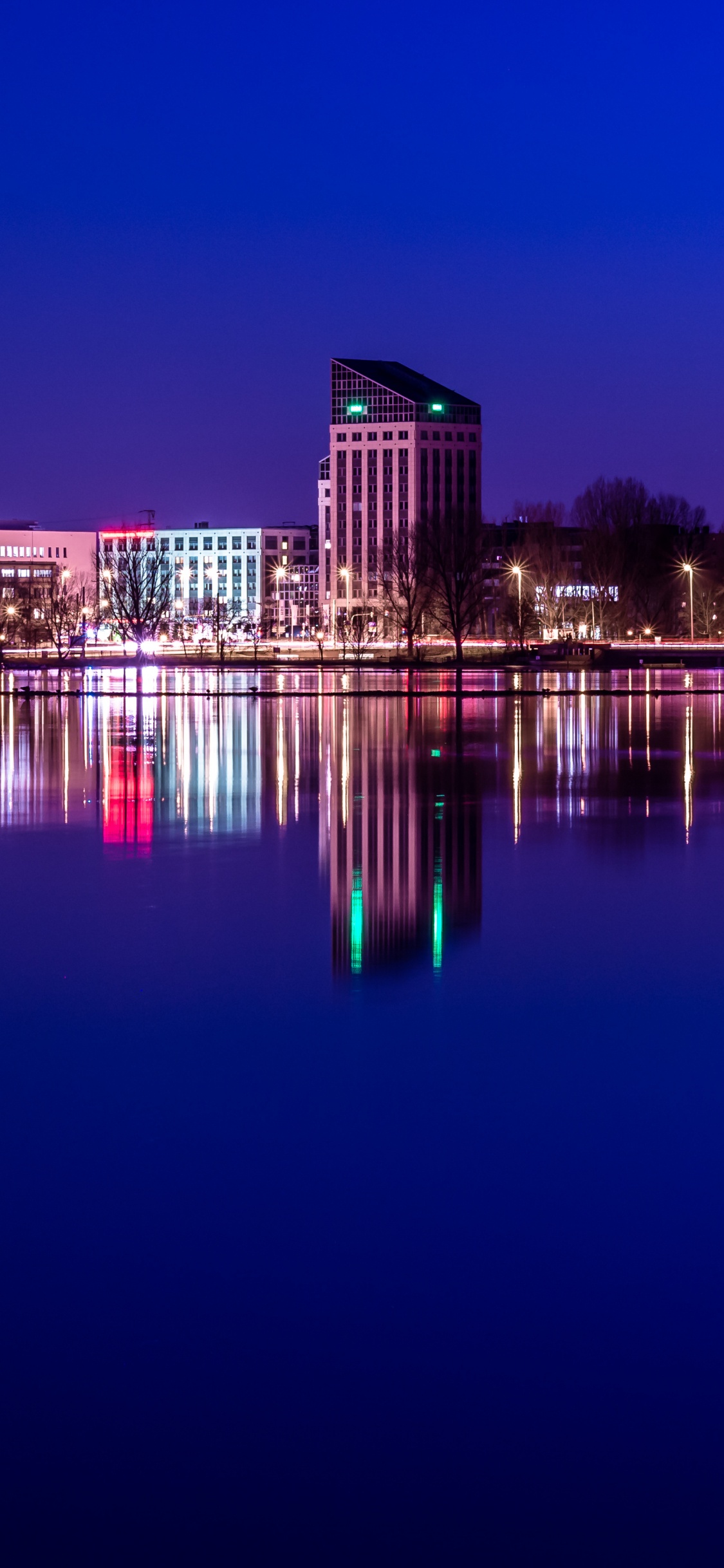 Bâtiment en Béton Brun Près D'un Plan D'eau Pendant la Nuit. Wallpaper in 1125x2436 Resolution