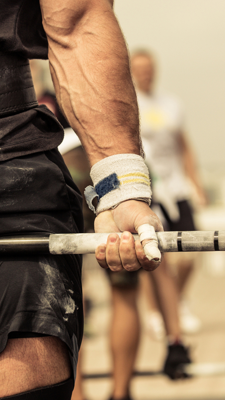 Man in Black Shorts Holding Barbell. Wallpaper in 750x1334 Resolution