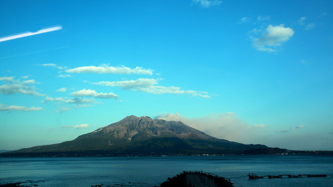 Montaña Verde Cerca Del Cuerpo de Agua Bajo un Cielo Azul Durante el Día. Wallpaper in 1366x768 Resolution